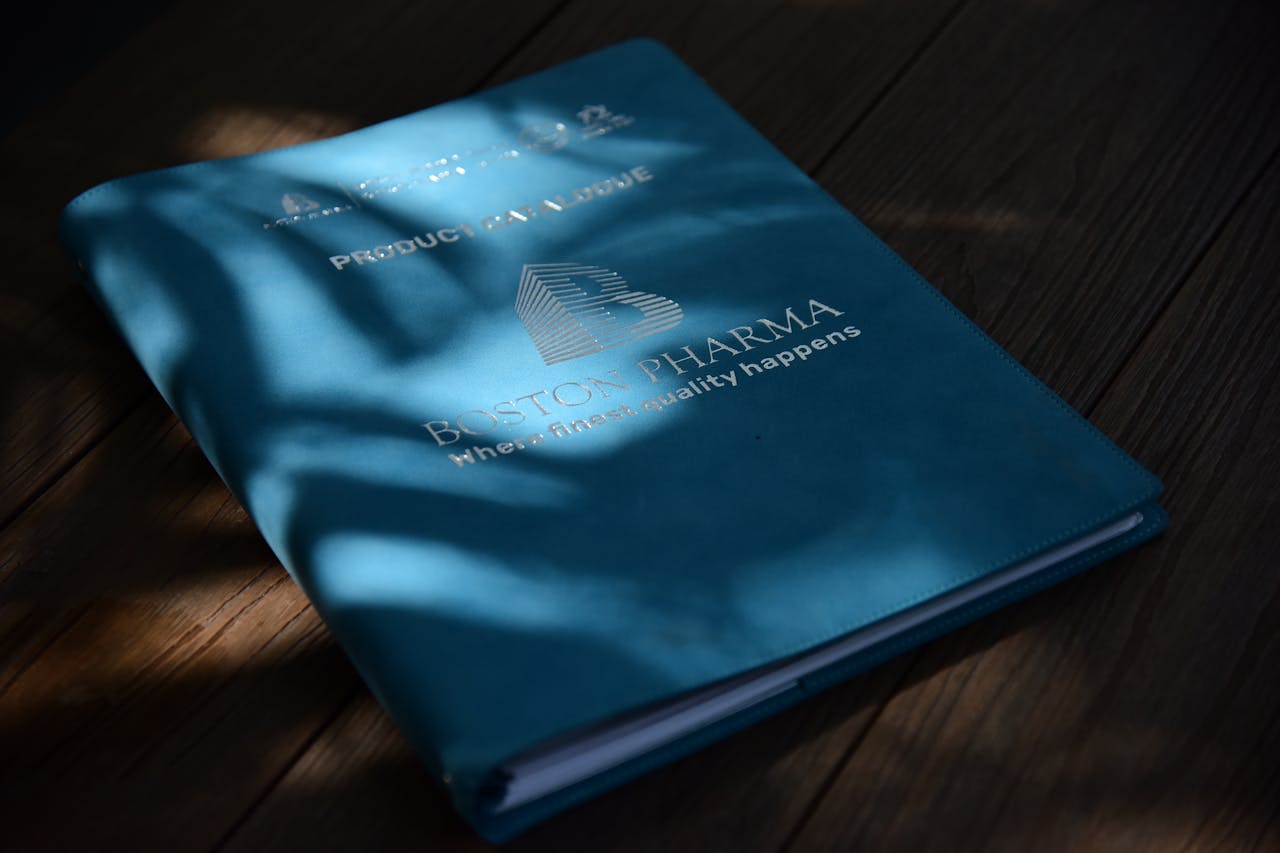 A blue folder with Boston Pharma branding in natural light on a wooden surface.